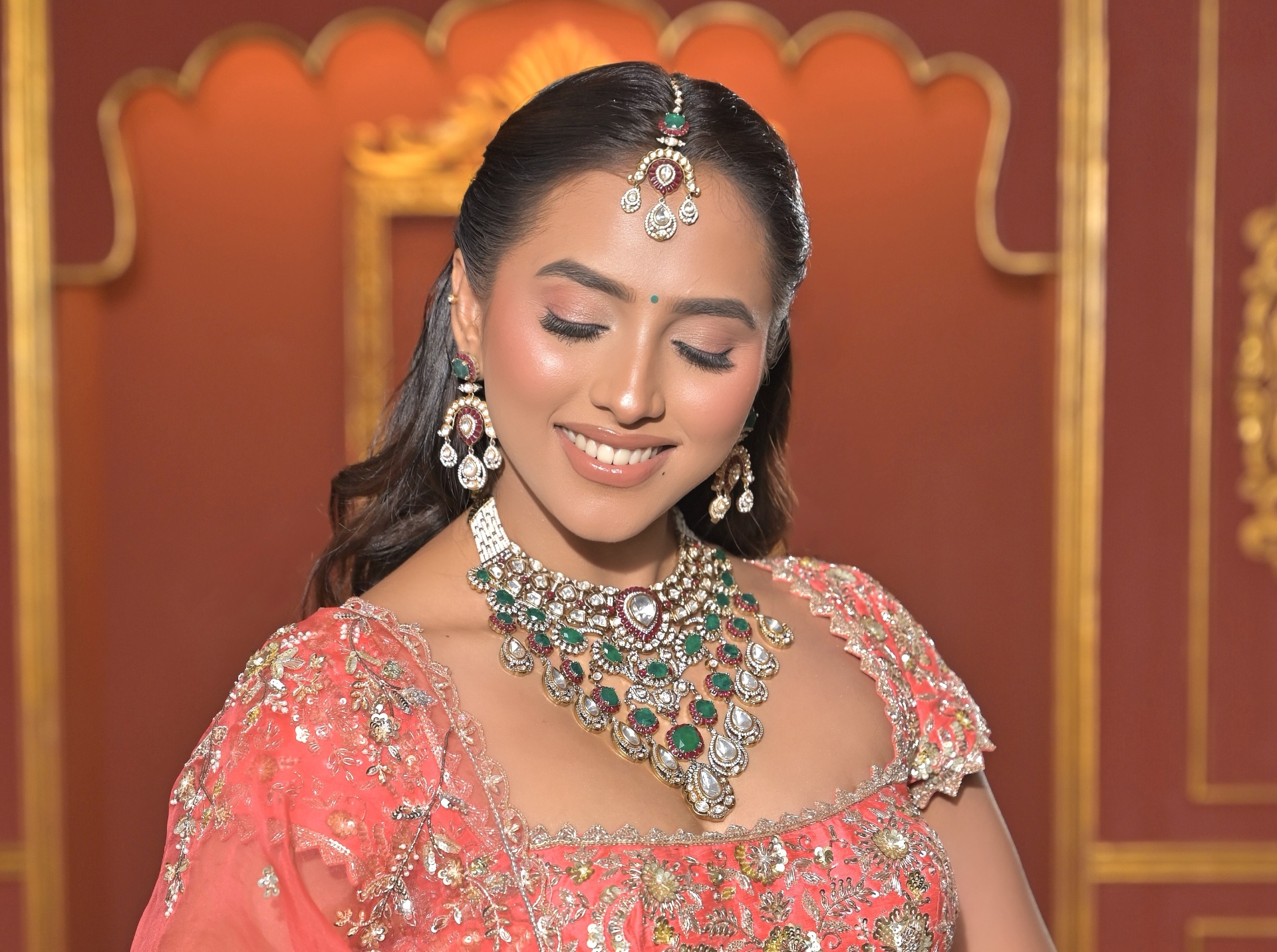 Bridal portrait in ornate coral ensemble with statement jewelry